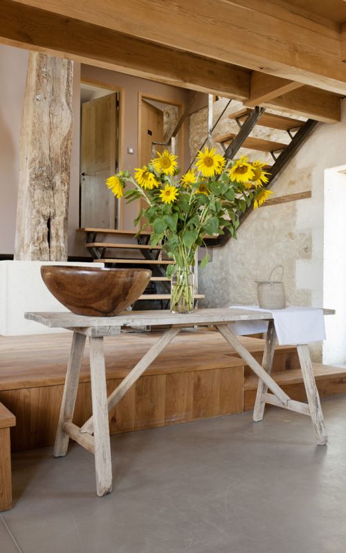 A vase of sunflowers stand on an old wooden table